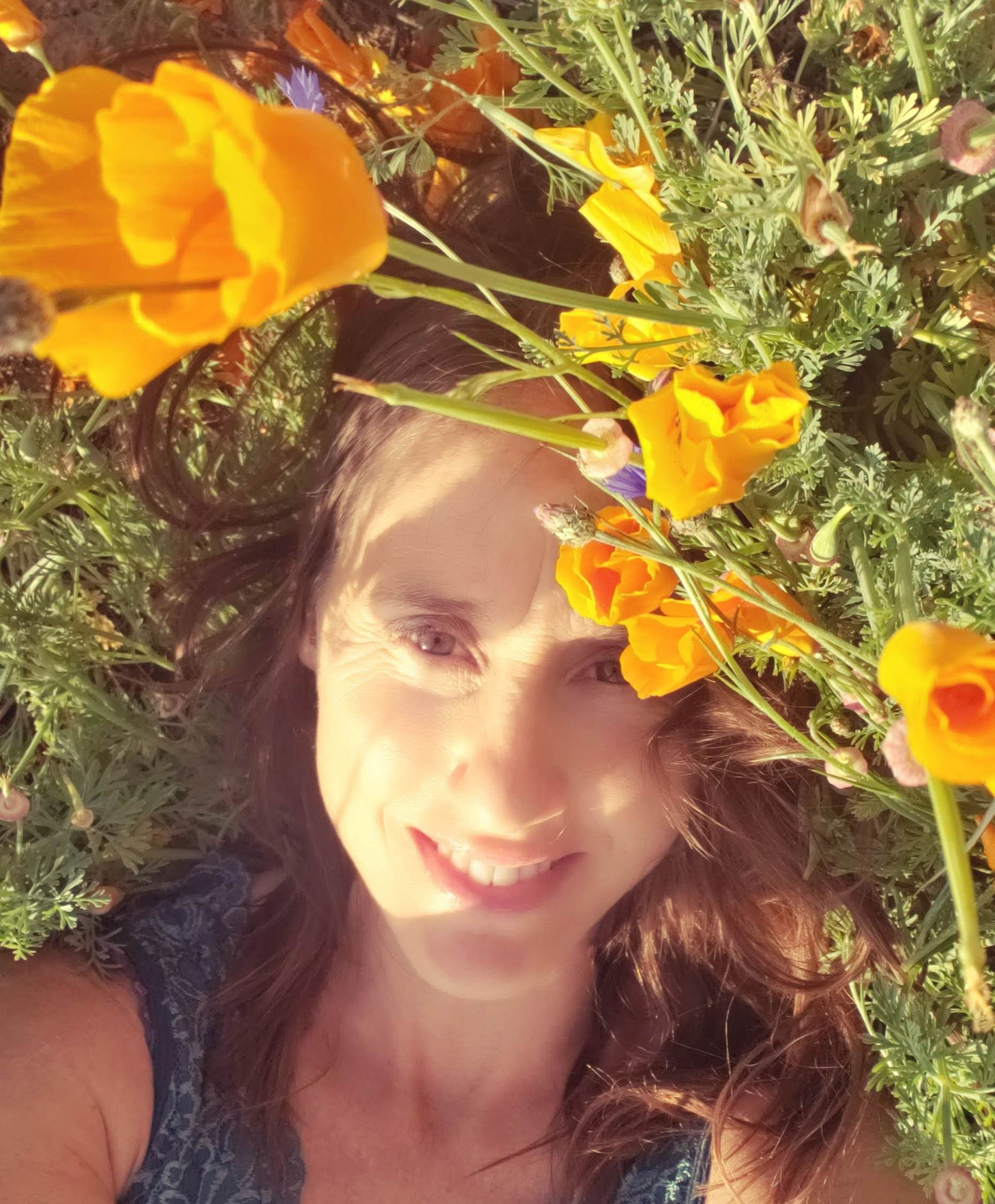 Raphaela lying among orange poppies, smiling